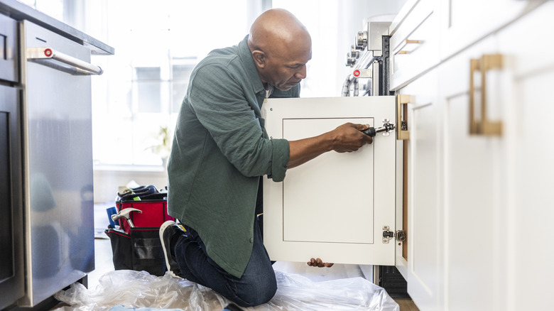 A man fitting refaced kitchen cabinet doors