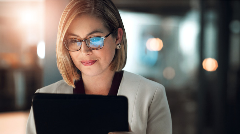 A woman in business attire reads from her tablet