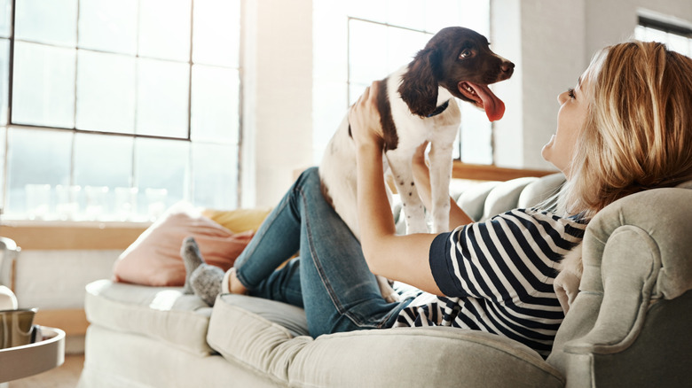 A woman lounges on a small sofa with her dog