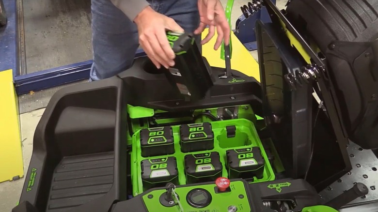 person changing batteries on Greenworks mower