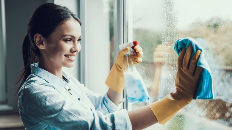 Woman wiping window spray bottle