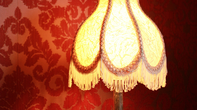 Fringed lampshade with red wallpaper