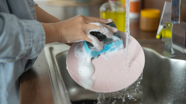 Woman hand-washing light pink plate