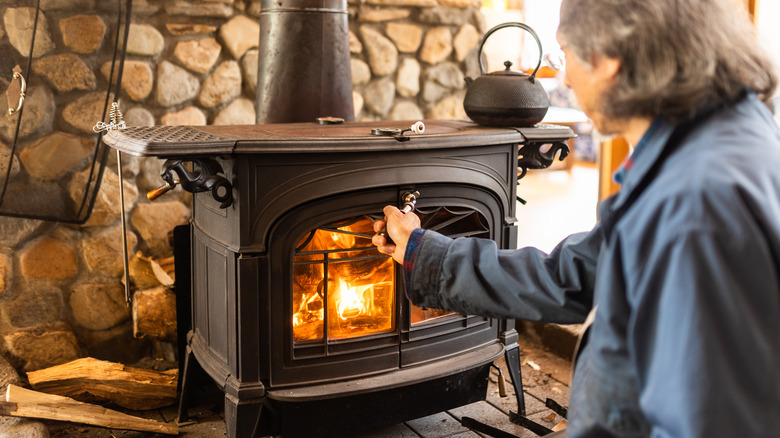 Person lighting a wood-burning stove 