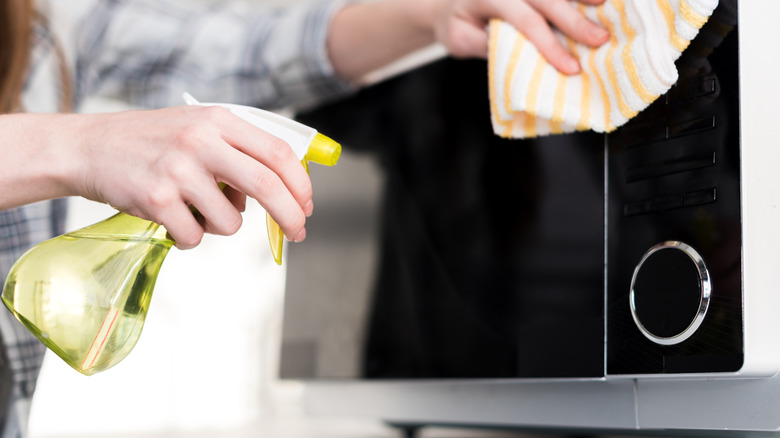 Person spray cleaning microwave