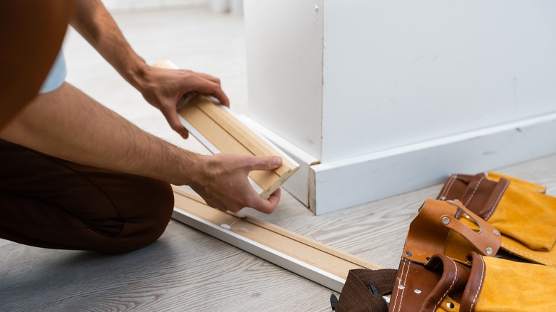 Man holds baseboard installation