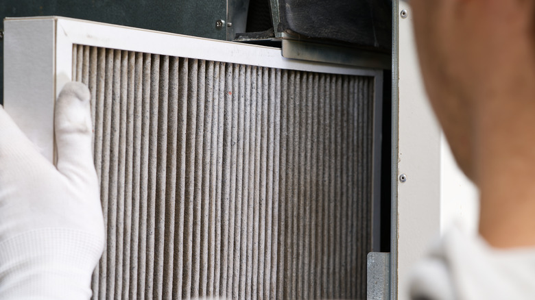 A person removing a dirty furnace filter