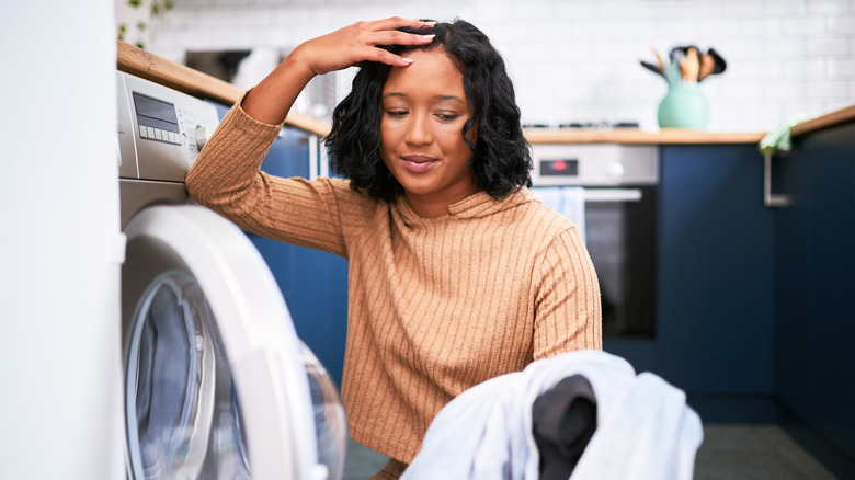 Woman with hand on head looking at laundry out of washer