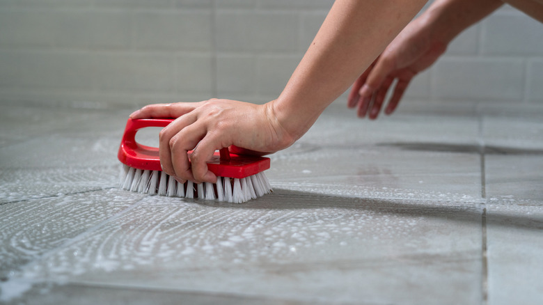 Person using scrub brush to clean marble tile flooring