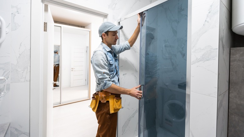 Handyman installing glass door in bathroom