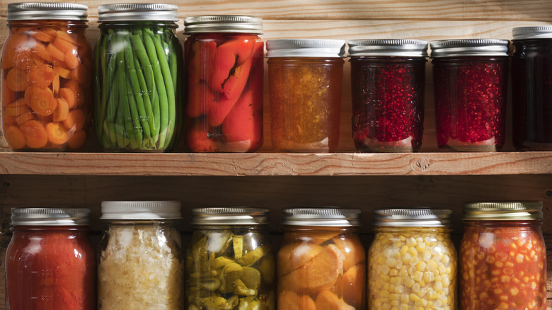 Two shelves with vegetables, fruits, and jams in canning jars