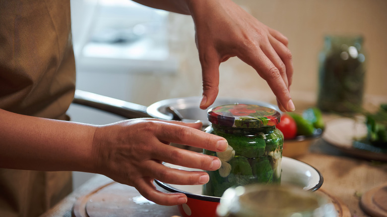 A person opening a jar of canned pickles