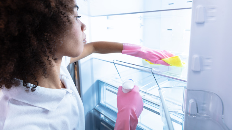 Person wiping refrigerator interior