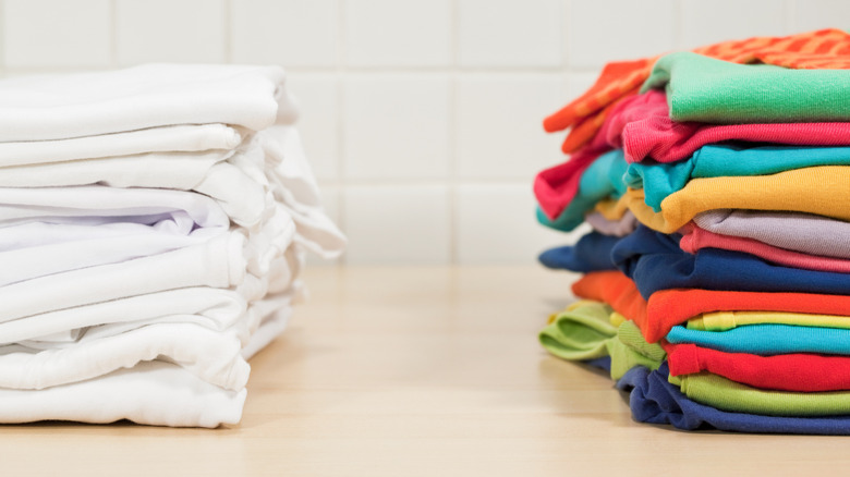 Stack of folded white laundry next to stack of folded colored laundry