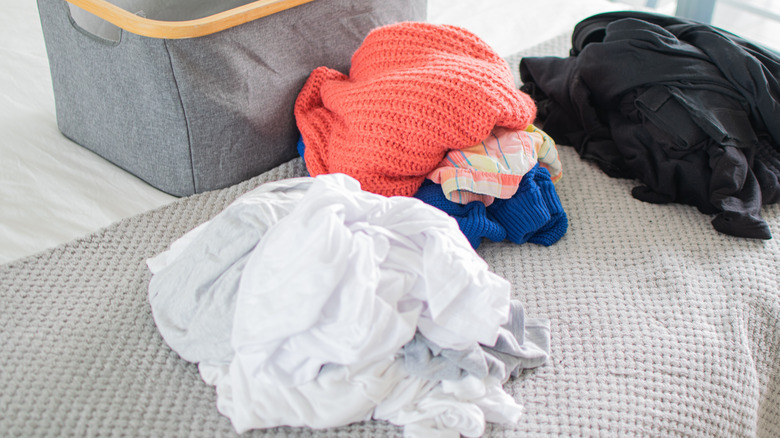 Laundry sorted into three separate piles on bed