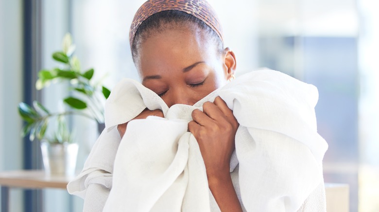 woman smelling white sheets