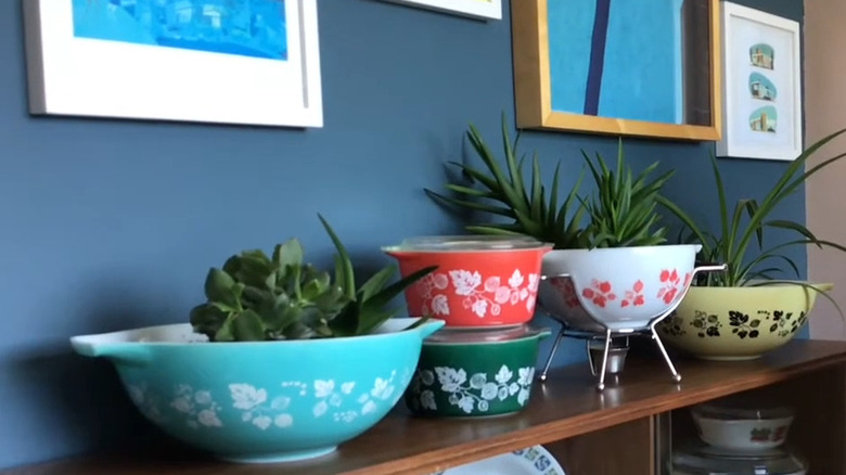 Collection of colorful vintage Pyrex bowls used as planters