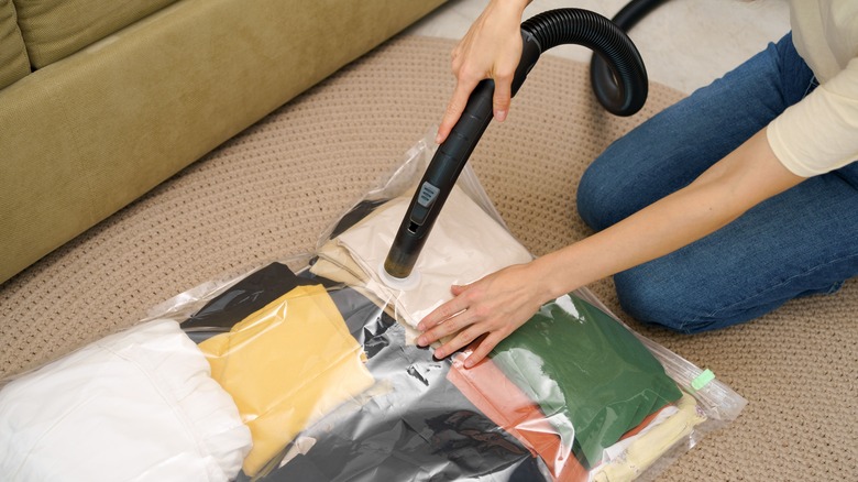 person using a vacuum hose to remove air from a plastic bag