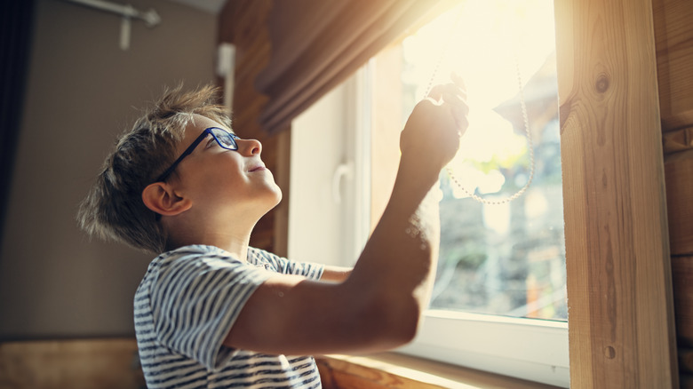 boy closing blinds