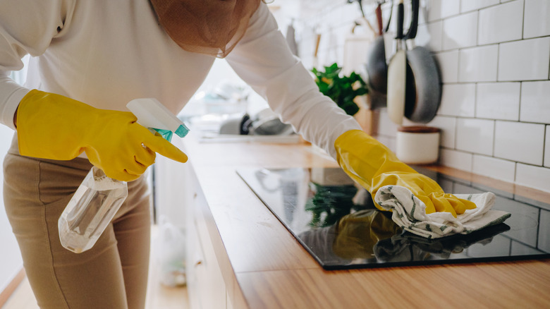 person wipes away grime from stove top