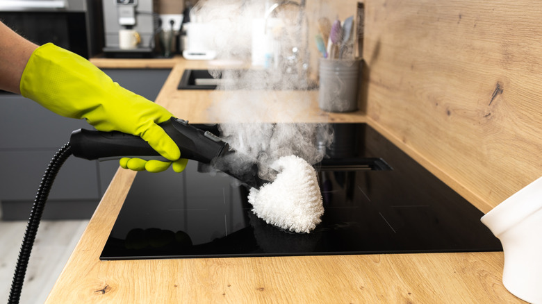 person uses steam cleaner on stove top