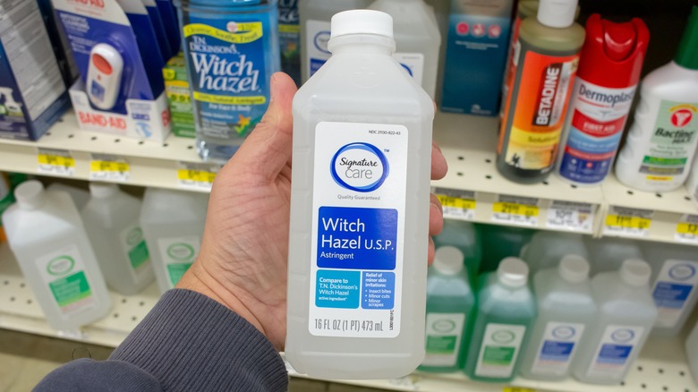 Person holding witch hazel bottle