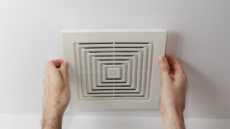 Person holding the cover of a bathroom fan