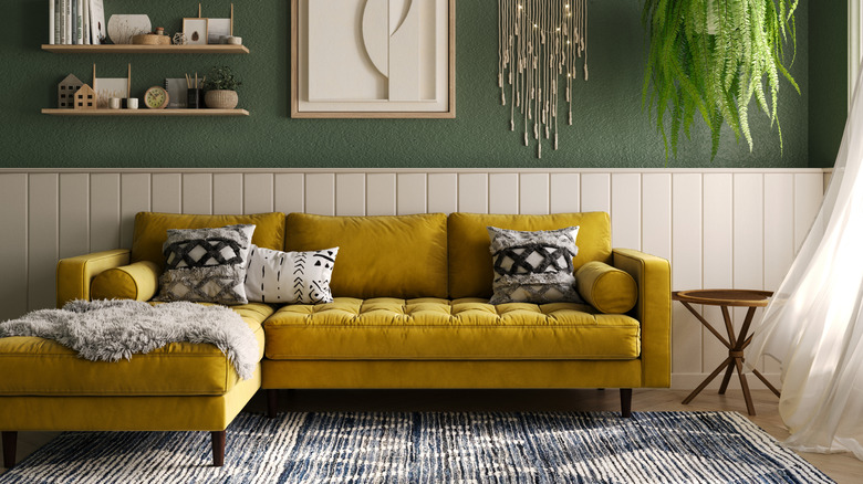 Living room with gold couch, green walls, and white accents