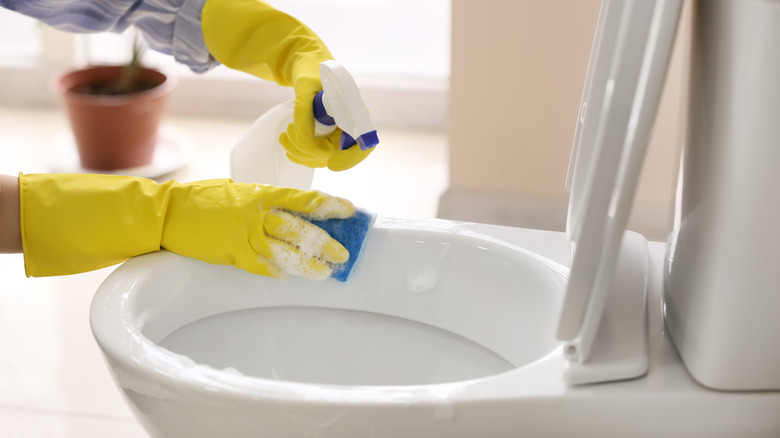 yellow gloves cleaning toilet bowl