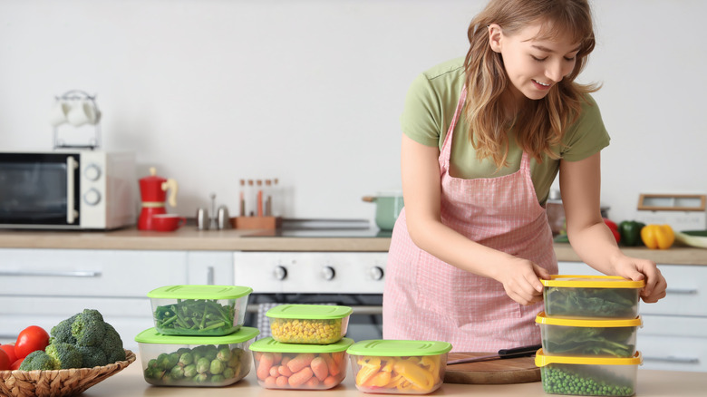 smiling woman packing vegetables in plastic food containers