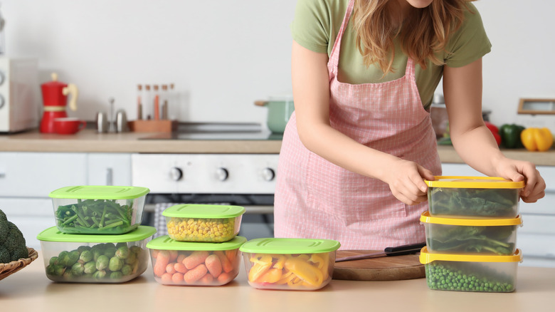 smiling woman packing vegetables in plastic food containers