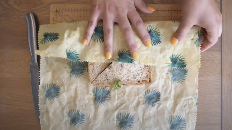 woman wrapping sandwich in plant patterned beeswax wrap