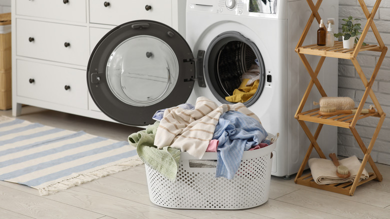 Basket filled with dirty clothes near front loading washing machine