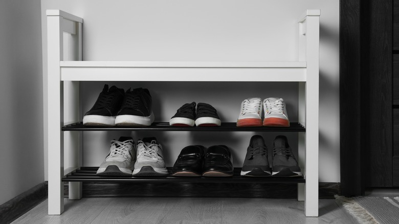 Shoes neatly arranged on white and black shoe rack near door