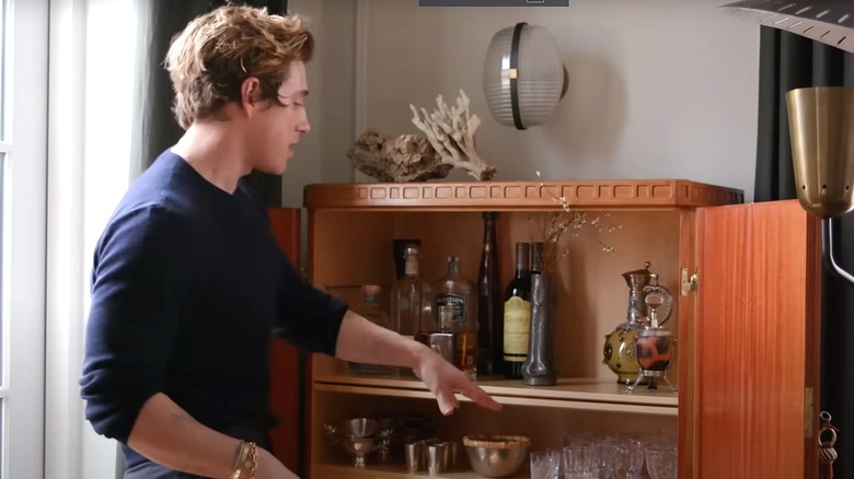 Jeremiah Brent gesturing toward shelves in wooden cabinet