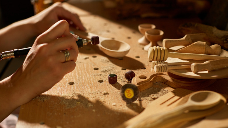 A Caucasian person uses a Dremel for a woodworking project