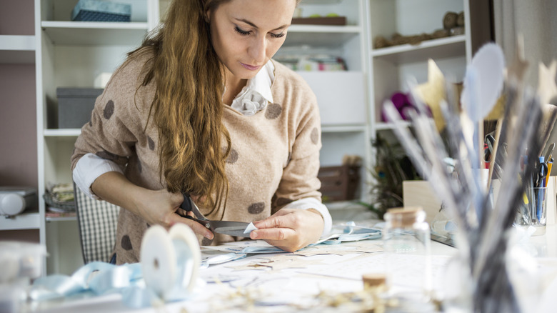 A brown haired Caucasian woman works on a scrapbooking project