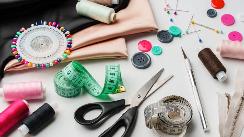 A work surface is scattered with sewing supplies