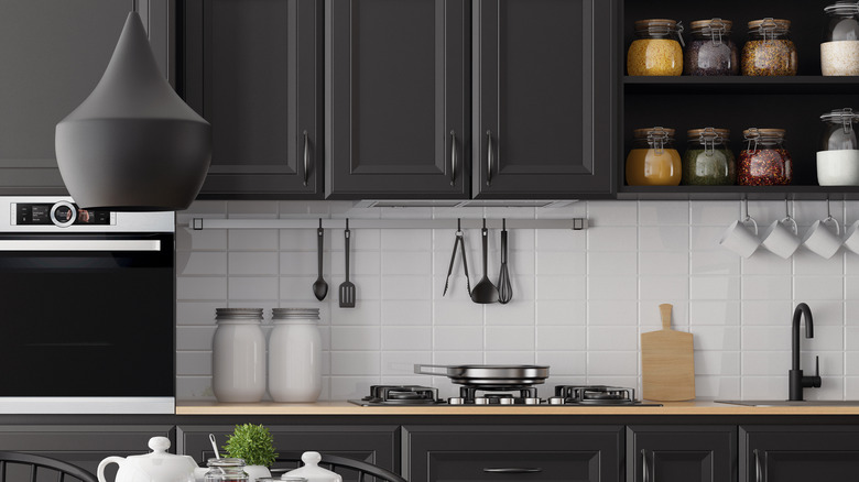 A kitchen with black cabinets and white tile