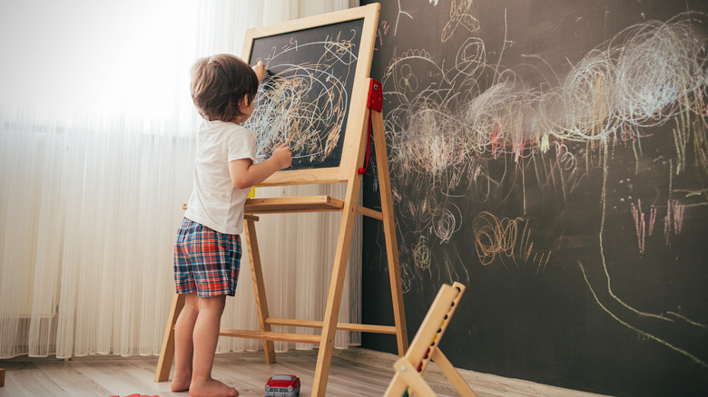 child with chalkboard and chalkboard wall
