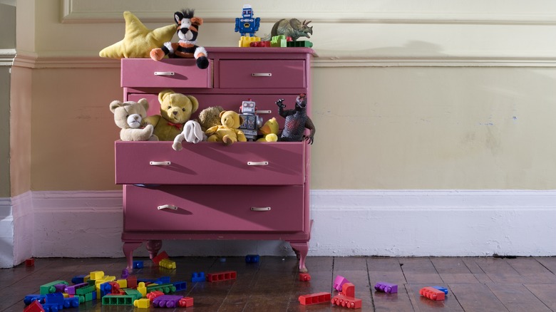 Pink chest of drawers overflowing with kids toys