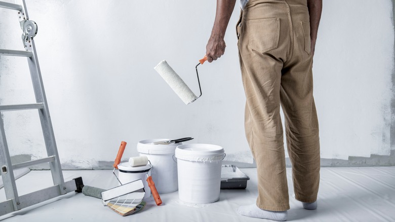 man holding white roller brush