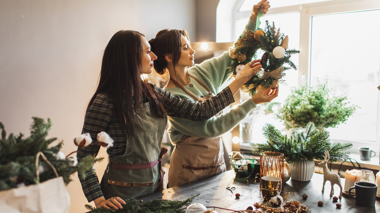 Two women crafting a green Christmas wreath