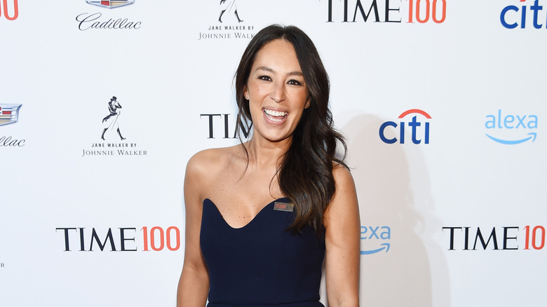 Joanna Gaines smiling at event while wearing navy blue dress