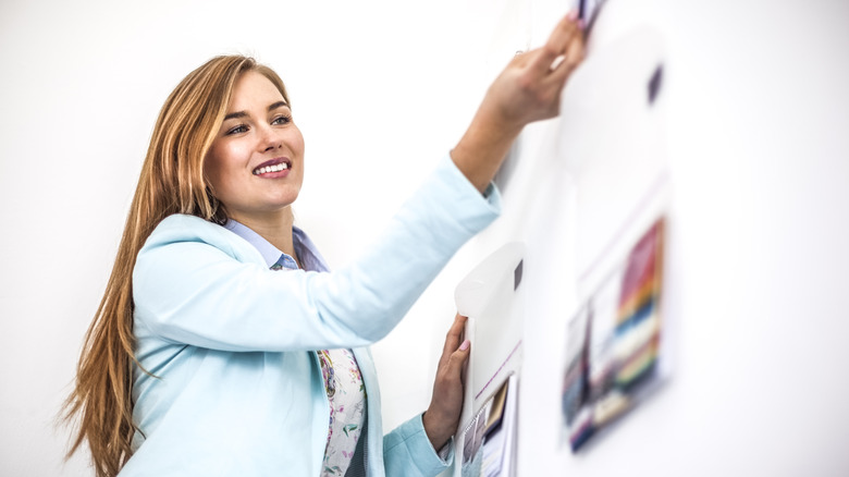 Woman hanging papers on wall