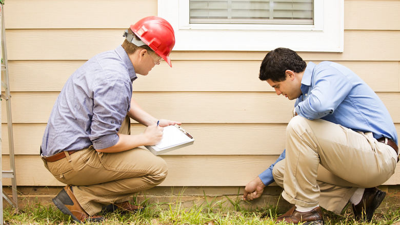 Two men inspecting foundation of a home