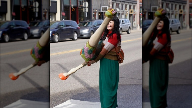 Katie Saro carrying ostrich sculpture across crosswalk