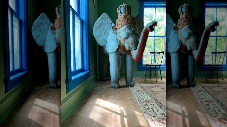 Elephant statue in corner of room with green walls and blue windowsills