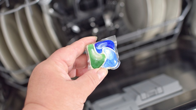 A person holding dishwasher pod over an open dishwasher