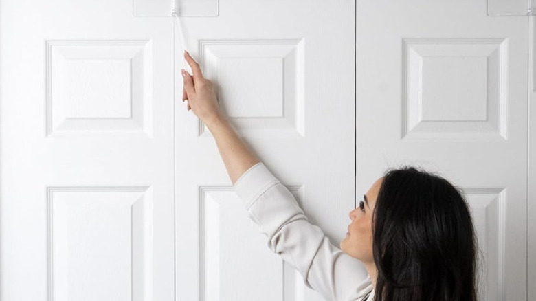 Woman installing bifold closet child-proof lock